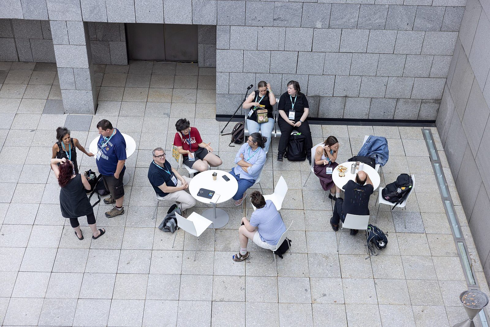 Vue plongeante en 2026 : de petits groupes discutent autour de tables rondes pendant une rencontre à Paris.